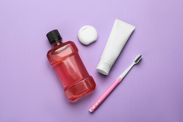 Mouthwash, toothbrush, paste and dental floss on violet background, flat lay
