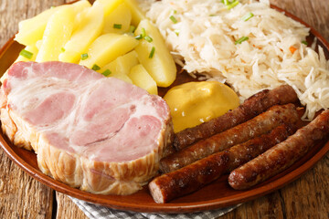 German Kassler pork neck with Sauerkraut potatoes and mustard on wooden table closeup in the plate on the table. Horizontal