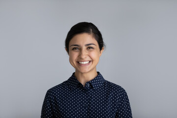 Headshot portrait of smiling millennial Indian woman isolated on grey studio background feel optimistic. Profile picture of happy young biracial female client customer show white healthy teeth. - Powered by Adobe