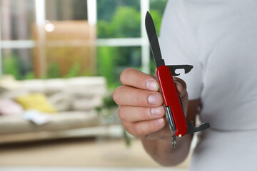 Man holding compact portable multitool indoors, closeup. Space for text