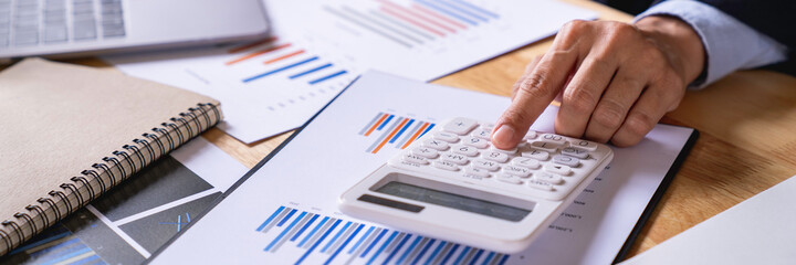 Businessman using the calculator to calculating invoice by coins and thermostat at the desk, Financial data analyzing. Counting on the calculator,taxes, bank account balance