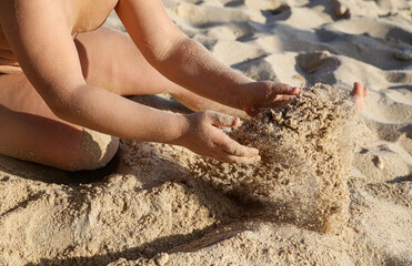 A boy plays in the sand on the beach near the sea.