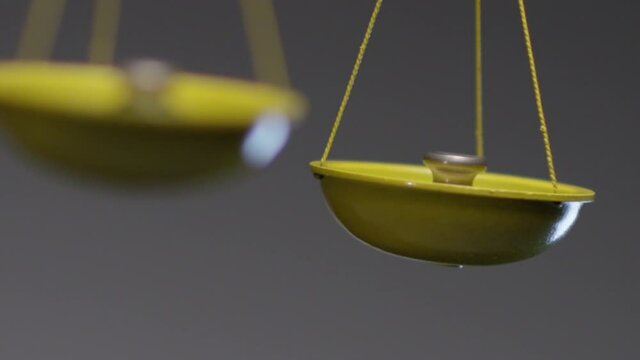 Yellow jewelry retro weigher . The scales are unsteady until they balance . Symbol of justice . Weights on the scales . Studio shot on RED EPIC Cinema Camera with strobe light .