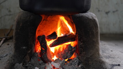 Bright reddish fire view, burning in clay stove, with wooden pieces. Traditional way to cook food...
