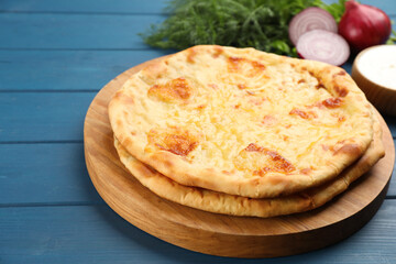 Delicious khachapuri with cheese on blue wooden table, closeup