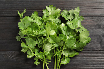 Bunch of fresh green cilantro on black wooden table, top view