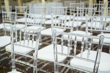 Glass chairs stand in a row in a beautiful wedding outing ceremony