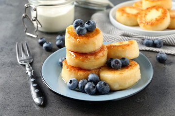 Delicious cottage cheese pancakes with blueberries and honey on grey table