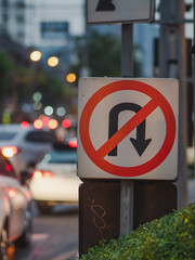 No U turn prohibited sign in a traffic light on busy roads with beautiful bokeh light.