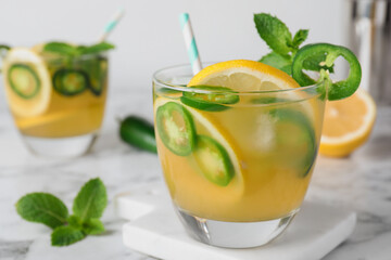 Spicy cocktail with jalapeno, lemon and mint on white marble table, closeup