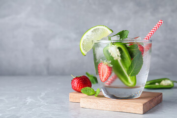 Spicy cocktail with jalapeno, strawberry, lime and mint on light grey table. Space for text