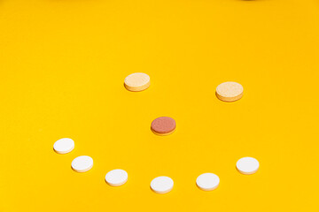 Some vitamin tablets agenced in a smiley face on a yellow background