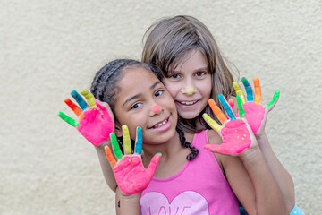 two beautiful happy girls playing together , best friends painting hands, diversity and...