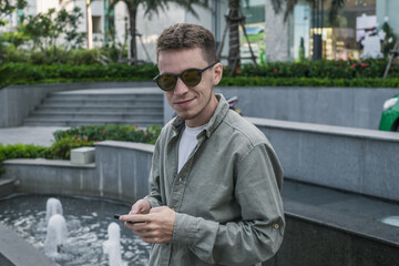 Fototapeta premium portrait of young caucasian man in sunglasses wearing light-green t-shirt and smiling. High quality photo