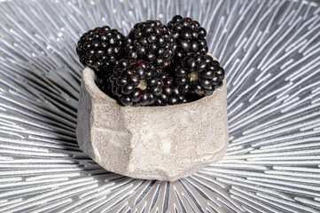 Fresh, large blackberries in a ceramic cup close-up. Macro, selective focus
