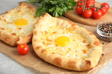 Fresh delicious Adjarian khachapuris served on grey table