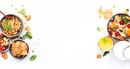 Muesli bowl and ingredients for healthy breakfast. Granola, nuts, dried fruits, flakes, honey and greek yogurt on white tableб copy space