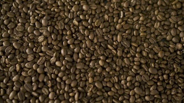 Close up of seeds of coffee. Roasted arabica coffee beans scattered on a  table. Fresh coffee beans. Espresso, americano, doppio, cappuccino, latte. Robusta. Coffee Texture detail. 