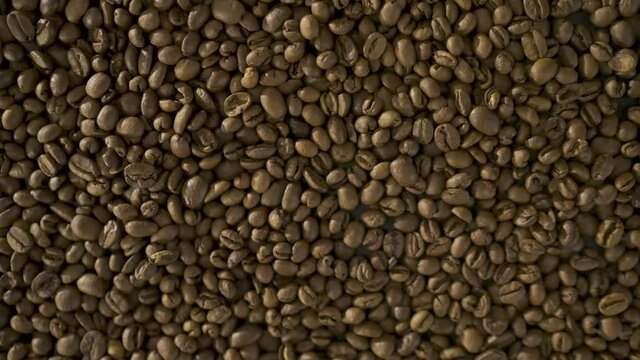 Close up of seeds of coffee. Roasted arabica coffee beans scattered on a  table. Fresh coffee beans. Espresso, americano, doppio, cappuccino, latte. Robusta. Coffee Texture detail. 