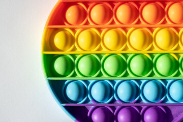 Close up round multicolored pop it toy and shadow on a white background. Colorful backdrop and copy space.
