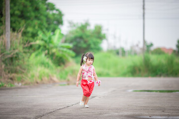 Close-up background view of a blurred Asian girl running or teasing in the street in front of the...