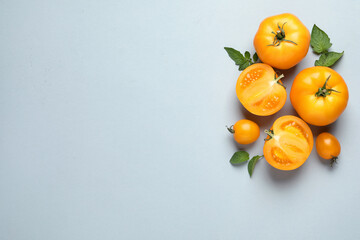 Cut and whole ripe yellow tomatoes with leaves on light background, flat lay. Space for text - Powered by Adobe