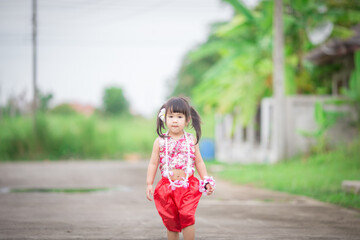 Fototapeta premium Close-up background view of a blurred Asian girl running or teasing in the street in front of the house, doing activities together outside the classroom during the holidays.