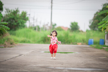 Fototapeta premium Close-up background view of a blurred Asian girl running or teasing in the street in front of the house, doing activities together outside the classroom during the holidays.