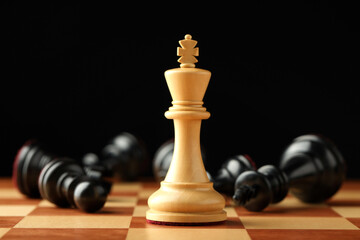 Chessboard with game pieces on black background, closeup