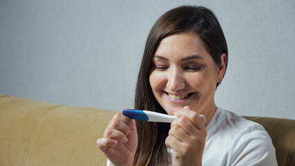 Close-up of young woman happily looking at pregnancy test.