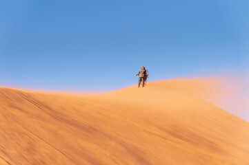 Naklejka na ściany i meble Positive attitude towards life. People walking on the sand dunes. Namibia, Africa.