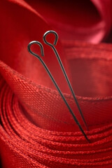 two sewing pins on the background of a red cloth tape. close-up.