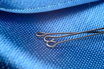three sewing pins on a background of blue fabric. close-up.