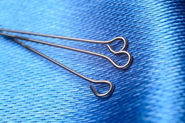 three sewing pins on a background of blue fabric. close-up.