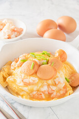 Creamy scrambled eggs with shrimp and sausage on top streamed rice for breakfast, white background