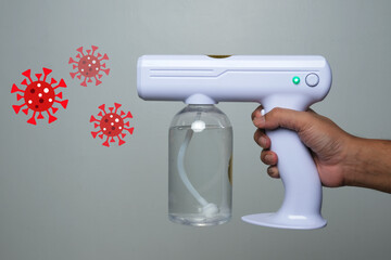 A picture of men hand holding wireless rechargeable nano blue ray atomizer spray gun and coronavirus