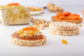 Puffed exploded wheat grains with peanuts and dried apricots on a thin layer of apricot jam on a background of oriental sweets on a white wooden table