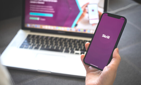 Kharkov, Ukraine - August 12, 2021: Skrill app. Woman using smartphone with skrill banking application. Brand logo photo