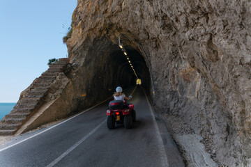 A road tunnel on the Spanish island of Mallorca. A young woman rides a quad bike. The inside of the...