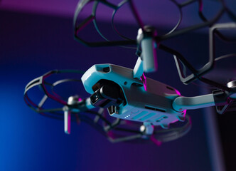 a small unmanned aerial vehicle with the protection of the propeller blades in flight on a neon background inside the room
