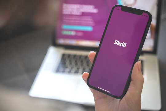 Kharkov, Ukraine - August 12, 2021: Skrill app. Woman using smartphone with skrill application. Brand logo photo