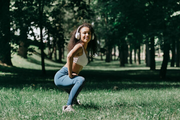 smiling young woman does morning exercises in the park.