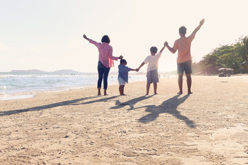 Happy family of four spend time and have fun together on summer holiday vacation, cheerful parents children hold and raise hand up from behind on tropical sea sand beach, resting and relaxing weekend