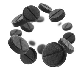 Black activated carbon tablets levitate on a white background