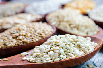 Closed up dry organic rice seed pile in wooden spoon on grunge background ready for healthy or diet food cooking