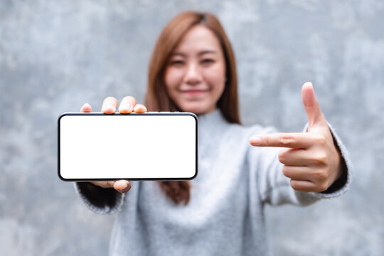 Mockup image of a beautiful woman pointing finger at a mobile phone with blank white screen