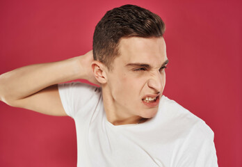 Obraz premium a man with an angry expression holds his hand behind his head white t-shirt Studio red background