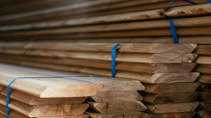 View of ends of stacked edged larch boards with beveled edge, planken for construction of fence or...