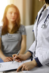 Close-up of woman-doctor and patient discussing current health examination while sitting indoors....