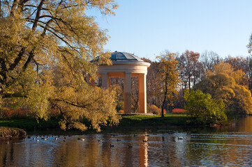 Gazebo and beautiful autumn trees in a city park by the lake on a sunny day